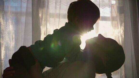 母亲抱着一个小孩阳光从窗户射进来宝宝的笑声和欢乐