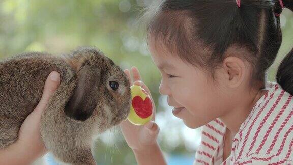 亚洲小女孩拿着复活节彩蛋期间看着小兔子的眼睛