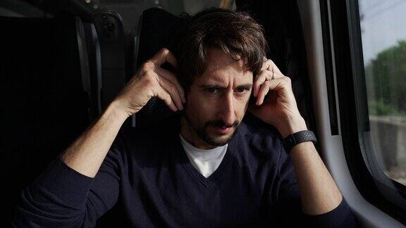 坐火车通勤时戴耳机的男子男乘客戴着降噪耳机听音乐播客或有声读物