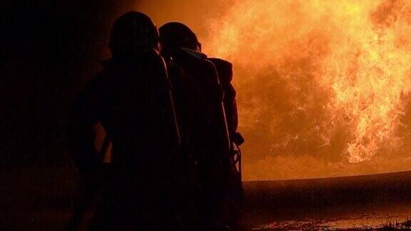 消防队员用旋水雾式灭火器来灭火火苗从油中涌出控制火势不向外蔓延消防和工业安全概念