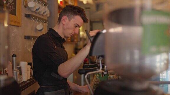 咖啡店里男咖啡师一边用浓缩咖啡机煮咖啡