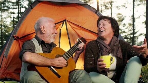 野外露营的老年情侣弹吉他唱歌