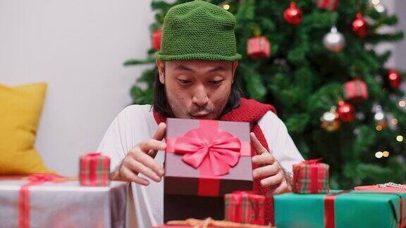 特写快乐的年轻亚洲人打开和惊喜的圣诞礼物礼盒在庆祝派对慢镜头