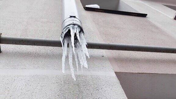 冬天屋外墙上的排水管上挂着冰冻的冰柱