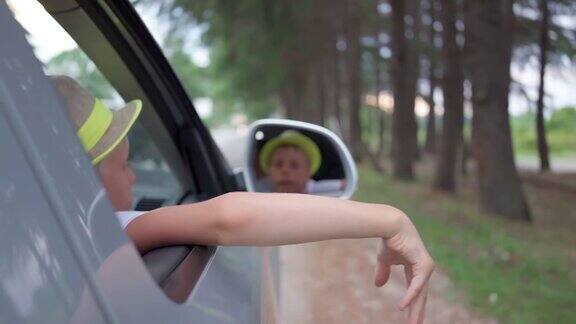 戴着帽子的男孩从城外的车里向我们挥手乘汽车旅行自由