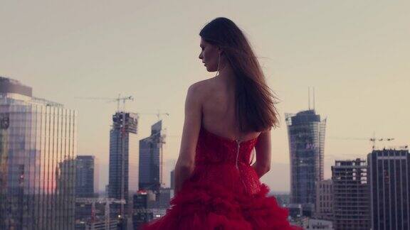在屋顶上跳舞的解放女性穿着红色的礼服欣赏城市全景