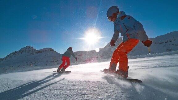 两名滑雪板运动员在阳光下下山