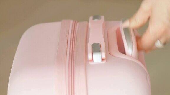 一个女人的手拉着一个粉色行李箱把手的细节镜头4k慢镜头