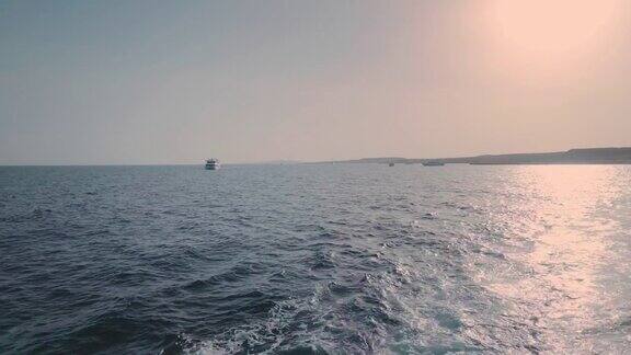 船在海面上的尾迹拍摄的夕阳这艘大船后面的水沫一直延伸到地平线