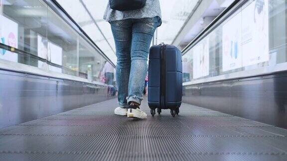 在机场的自动扶梯上向下看着提着行李箱的旅客