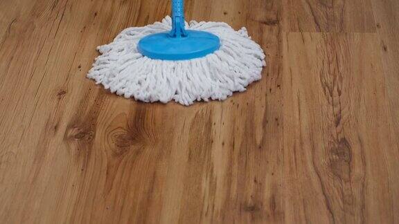 一个平坦的湿拖把前视图缓慢地来回擦拭客厅的镶木地板