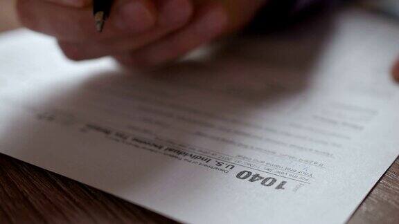 填写美国税单的人税务表由美国企业收入办公室手工填写概念特写镜头男子正在检查美国个人收入申报状态报税表1040