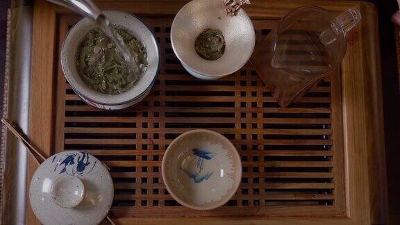师傅从盖湾的茶壶里倒热水茶几上放绿茶