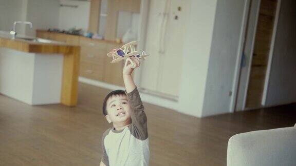 亚洲男孩拿着玩具飞机跑来跑去(慢镜头)