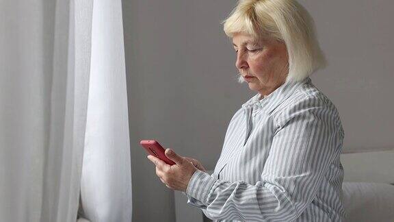 一位50岁的女士在家里拿着手机用wifi上网发短信