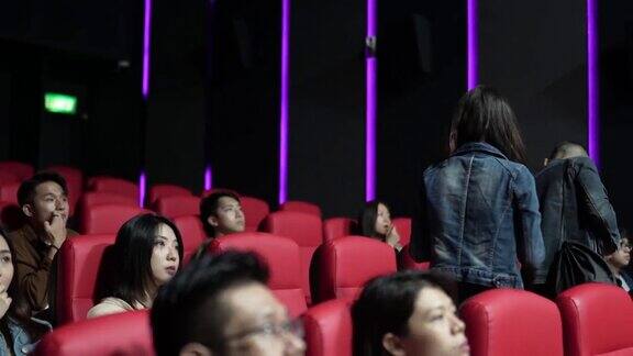 在电影放映期间一对亚洲华人夫妇进入电影院经过其他观众到达他们的座位