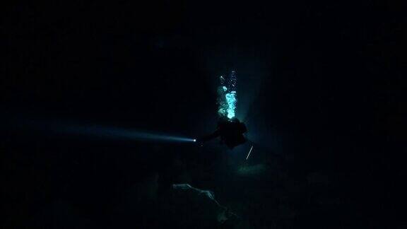 背光洞穴潜水员扫光黑暗的洞穴