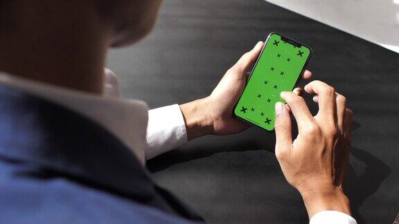 商务人士在办公桌边使用绿色屏幕的智能手机