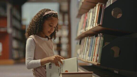 一个小女孩独自在图书馆里小孩子在做研究可爱的孩子在图书馆做作业