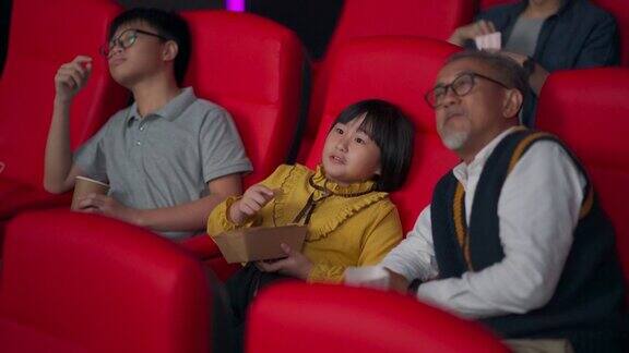 一位活跃的亚洲华人老人和他的孙辈们喜欢在电影院看电影