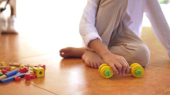 男孩在地板上玩木制汽车玩具