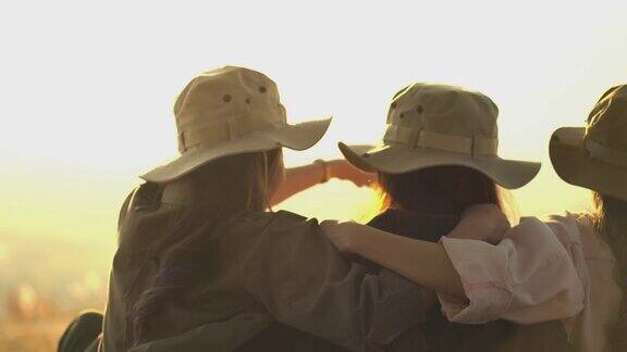 年轻女子坐在一起互相拥抱一起看日落