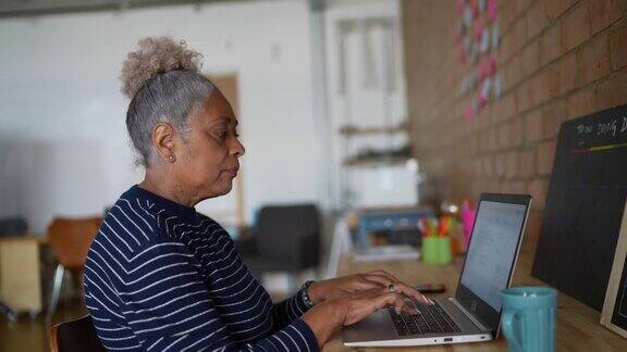 高级女性在工作时使用笔记本电脑