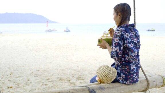 热带海滩上抱着新鲜冷椰子的女孩