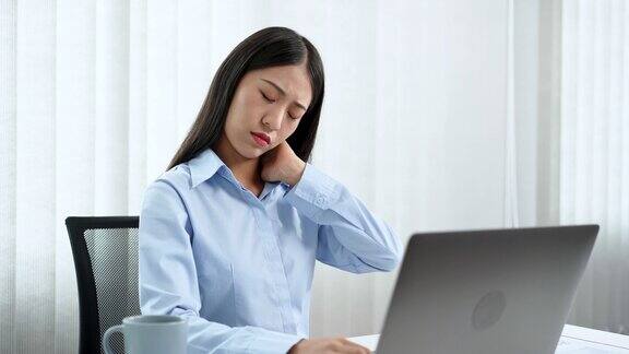年轻的亚洲商务女性在办公室用笔记本电脑努力工作因为颈部疼痛而做伸展运动热身和锻炼的4k视频片段