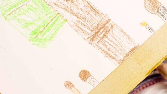 一个女孩在一张桌子上用蜡笔在纸上画画