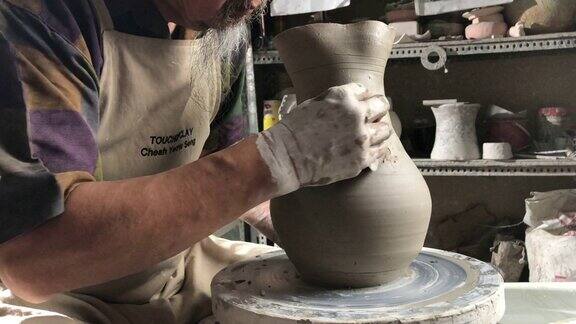亚洲华人高级陶艺师在他的工艺工作室里在一个旋转的陶轮上制作陶器