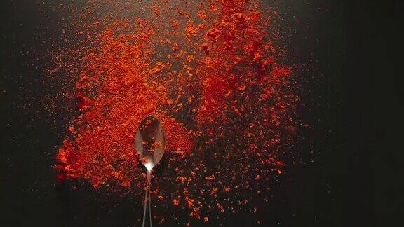 慢镜头:一勺红辣椒粉落在一张黑色的桌子上