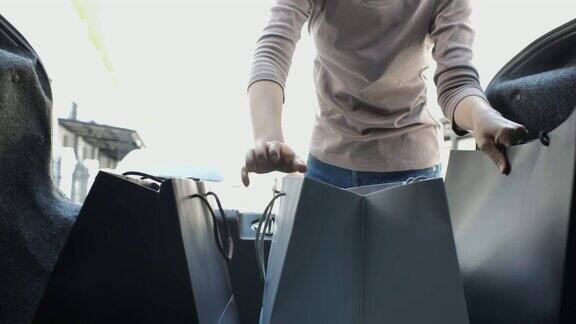一个女人把购物袋装进汽车后备箱