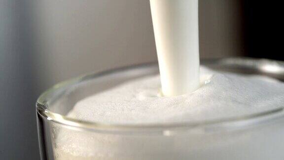 牛奶流进装满泡沫牛奶的玻璃杯里