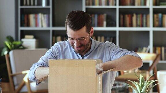 微笑的年轻人顾客打开包裹盒子坐在书桌