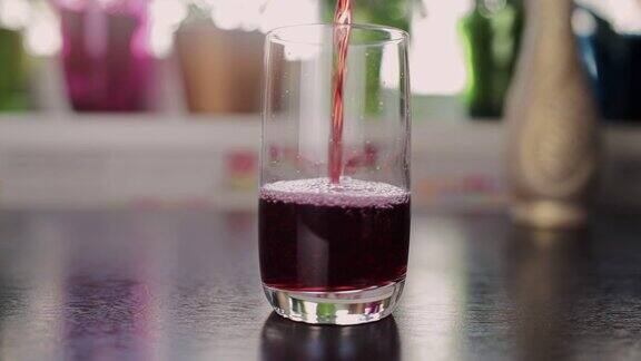 厨房里将樱桃汁倒进玻璃杯里