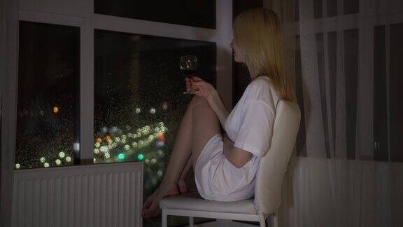 在夜色的城市背景下一个女人拿着一杯葡萄酒