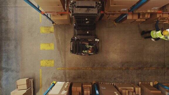 自上而下的无人机拍摄:电动叉车卡车操作员举起托盘与纸箱在一个大零售仓库的货架物流产品和货物配送中心