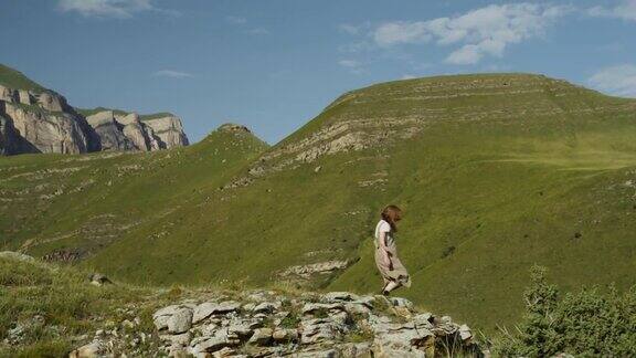 俄罗斯高加索地区一个年轻的女人走下山坡停在一个陡峭的石坡上