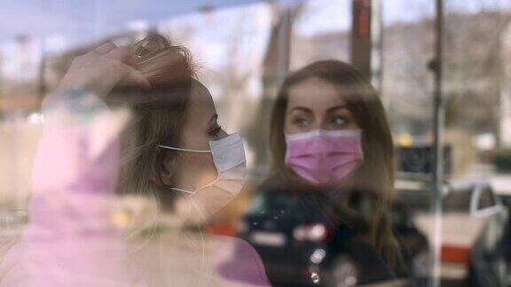 两名妇女戴着口罩坐在公共交通工具上
