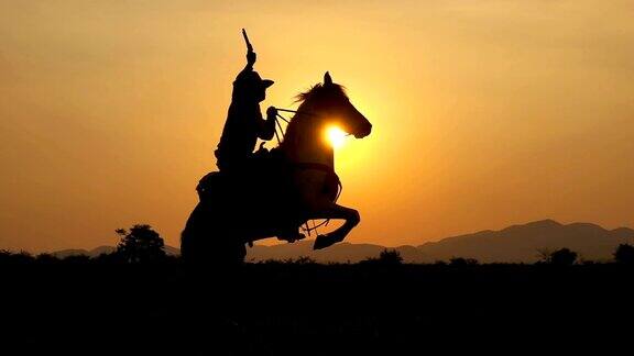 慢动作拍摄的牛仔骑马和拿着枪在日落