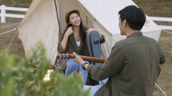 亚洲夫妇在营地里弹吉他一起唱歌