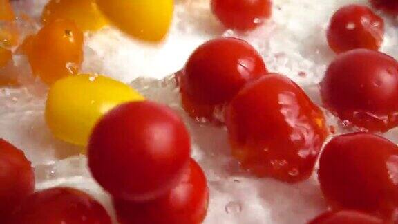 红色和黄色的樱桃番茄落入水中洗西红柿在白色背景上缓慢的运动