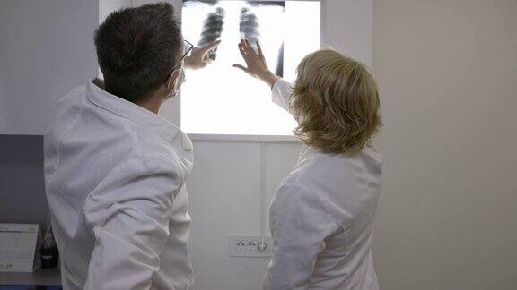 放射科医生戴着防护面罩在阴性镜上观察x光的后视图