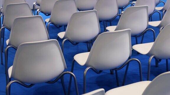 蓝色背景上的白色空椅子排成一排