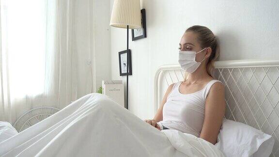 妇女咳嗽带着口罩躺在家里的床上