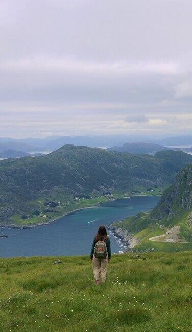 在挪威的西开普省背着背包的快乐女子凝视着大海和山脉的美景