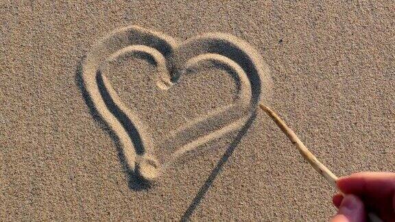 在日落时分用木棍在沙滩上画心形