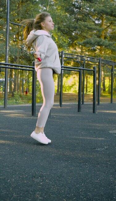 一名女子穿着运动服在公园的运动场跳绳的垂直视频