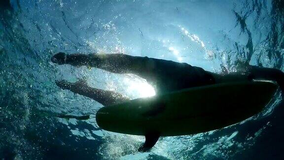 慢动作水下:运动冲浪者划桨在开放水域的海浪